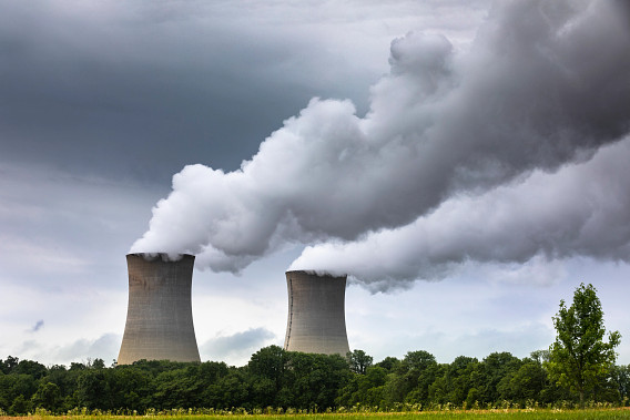 two smoke stack chimneys from a powerplant pumping steam and smoke into the sky